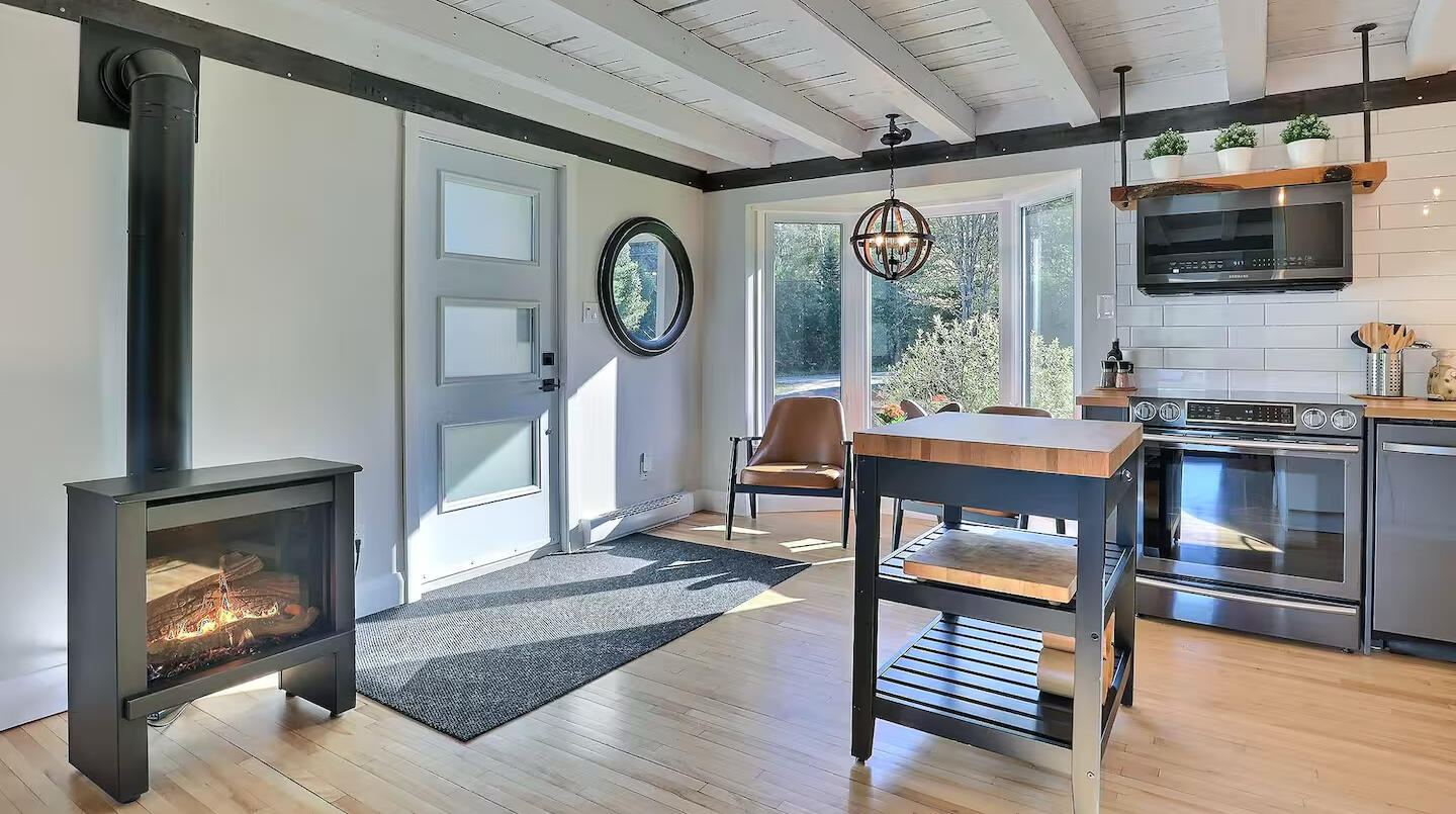 Cuisine et entrée du chalet Le Monarque près de Magog avec îlot central et foyer Cuisine lumineuse du chalet Le Monarque près de Magog avec îlot central, grandes fenêtres et foyer moderne